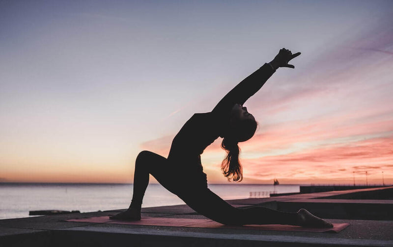 A person practicing yoga at sunset, embodying the spirit of 10 Tips For Achieving The Perfect Workout.