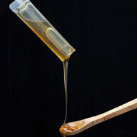 MGO 150+ Manuka honey gift package featuring premium Australian Manuka honey dripping from a spoon.