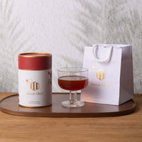 Ironbark Honey 360g in a stylish container with a glass of honey and a branded gift bag on a wooden platter.