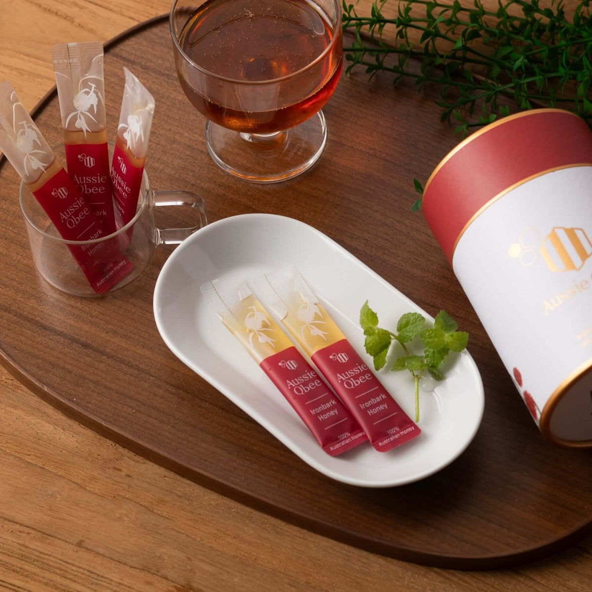 Ironbark & Macadamia Honey gift package displayed with tea and mint on a wooden table.