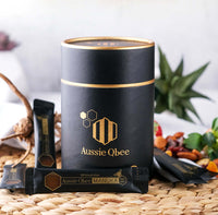 Manuka Honey MGO600+ Gift Package featuring Aussie Qbee black container and honey sticks on a rustic background.