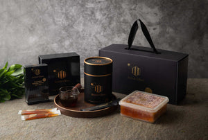Collection of black and gold products on a textured surface with a gray background